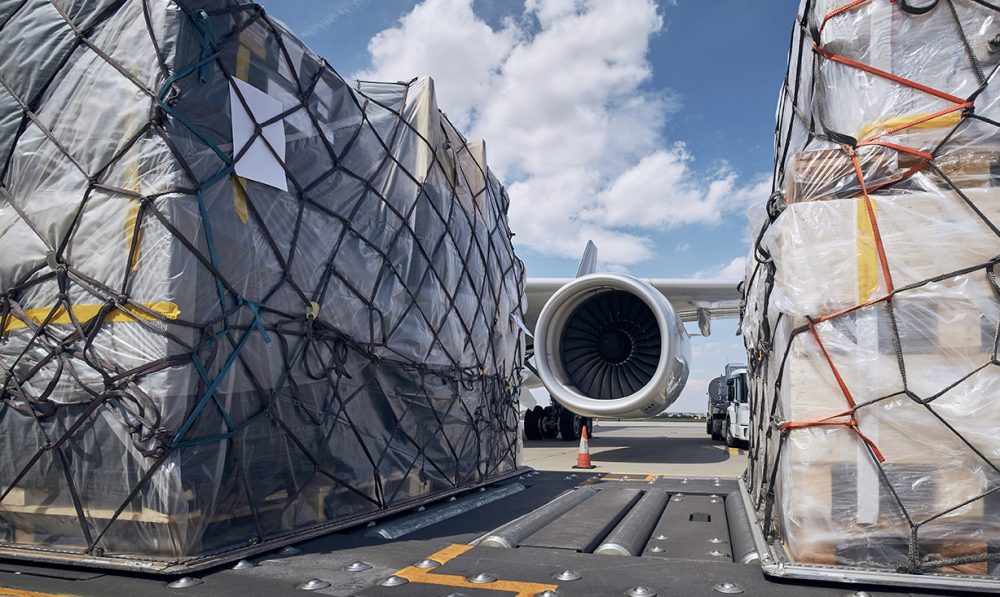 Preparation before flight. Loading of cargo containers against jet engine of freight airplane.